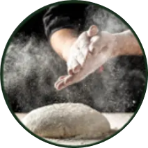 Hands dusting flour over dough ball.
